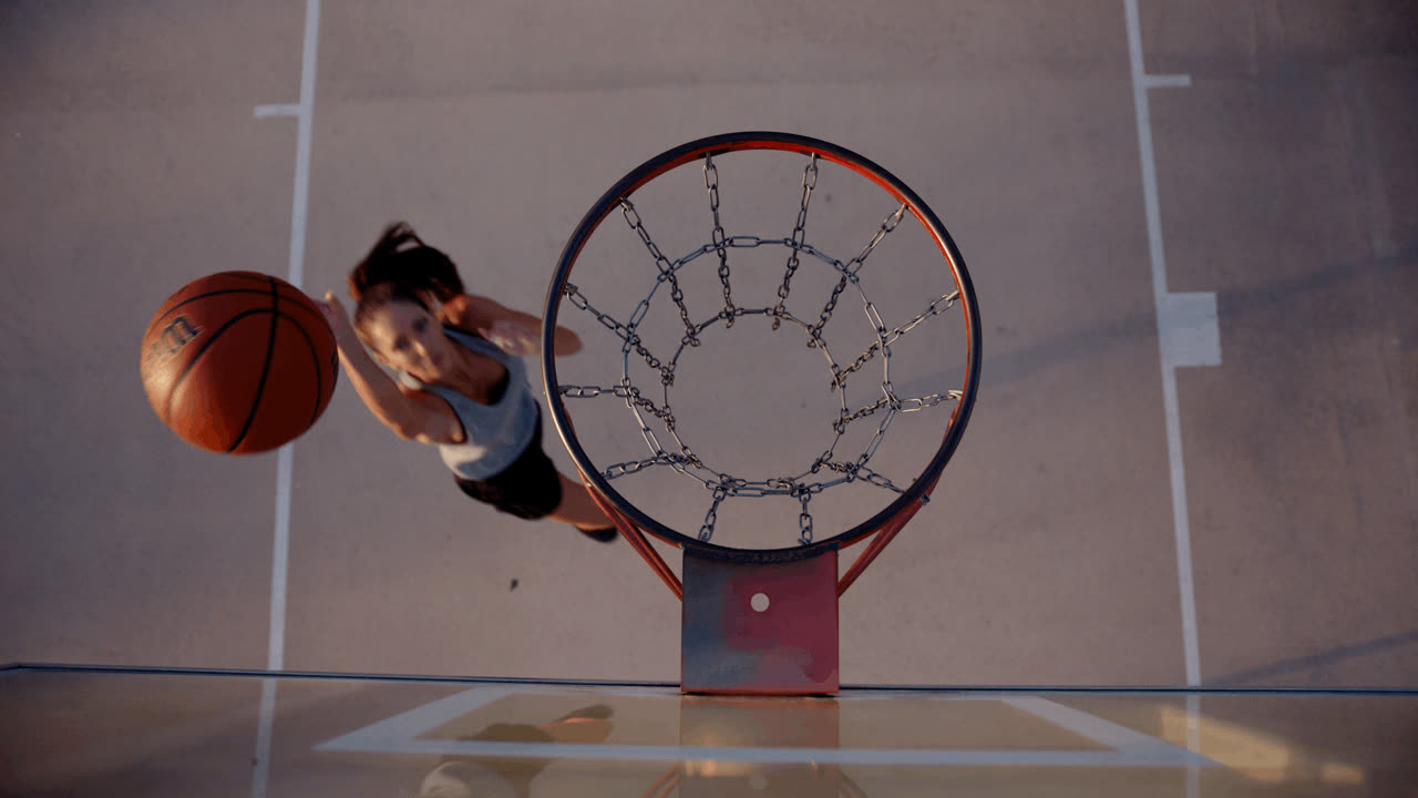 A basketball player going up for a layup, seen from directly above the hoop