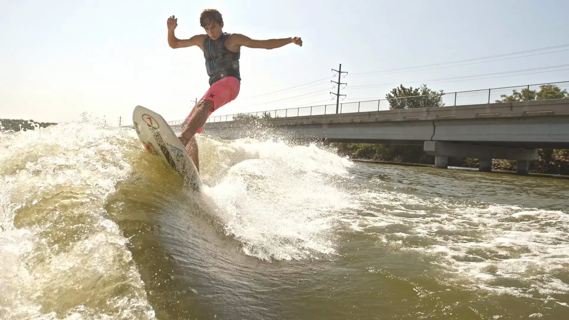 Low angle from the water as Parker Payne carves with his arms out, spray backlit
