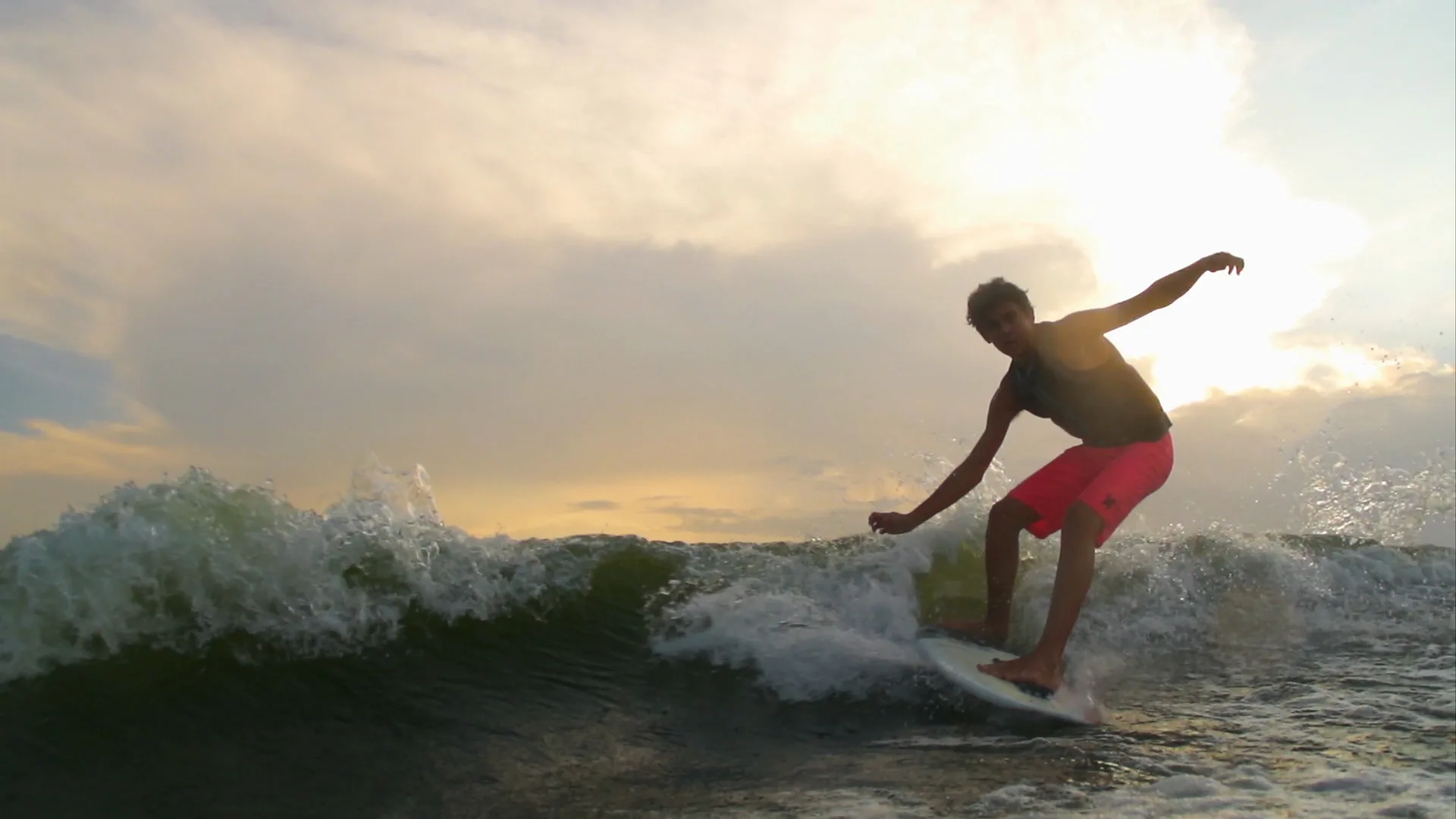 A backlit silhouette of Parker Payne riding the wave at sunset