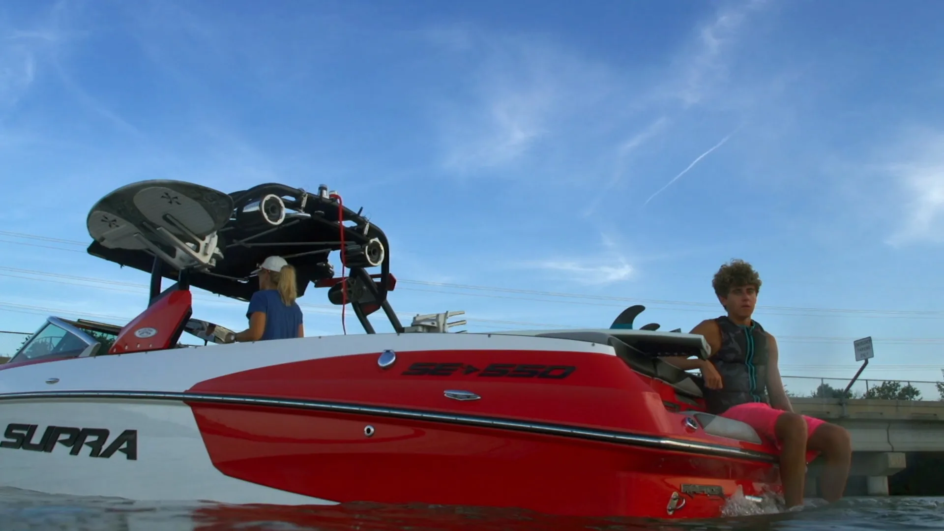 Parker Payne sitting on the Supra's swim platform under a blue sky