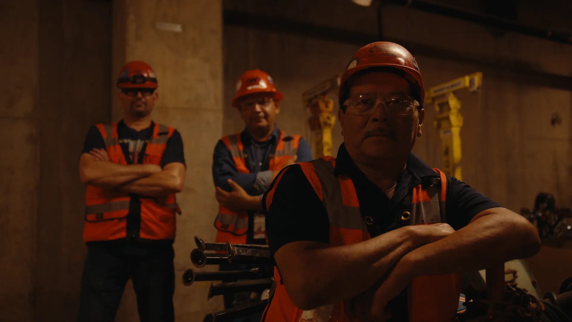 Two craft workers in hard hats with arms crossed on the job site
