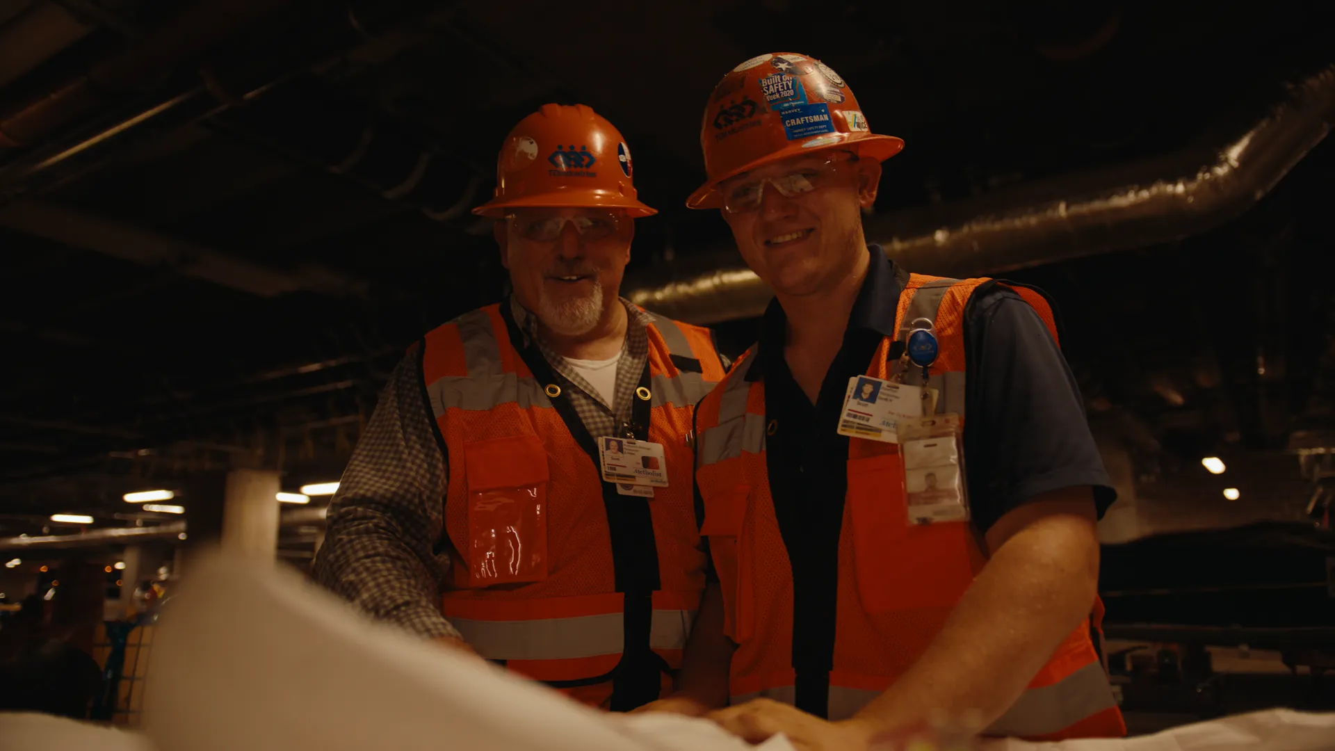 Two workers laughing over a set of plans