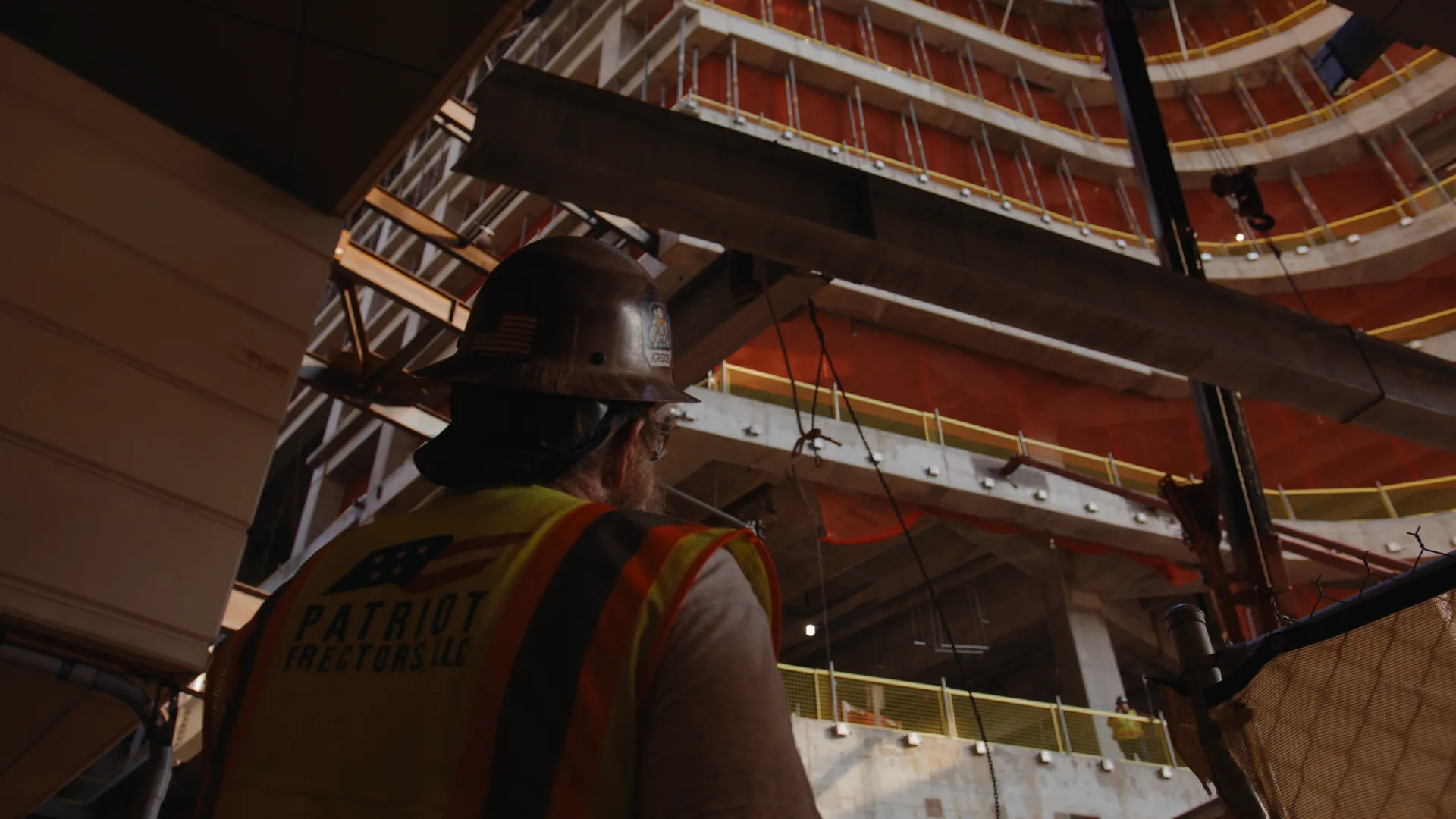 A worker looking up through the steel of a building under construction