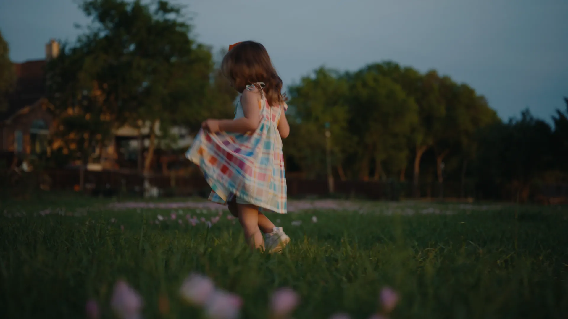 A girl twirling her plaid dress in a field of pink wildflowers