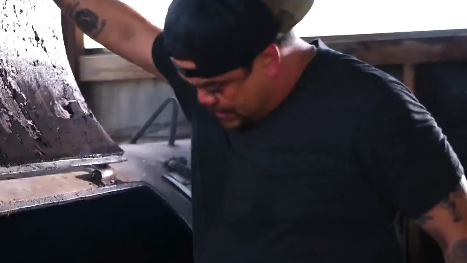 Pitmaster lifting the smoker lid in window backlight