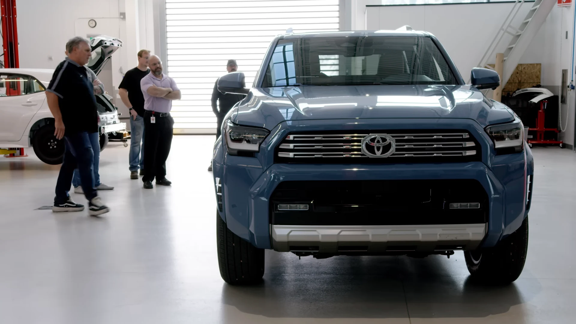 The stock blue 4Runner nose-on in the TRD shop as the team looks it over
