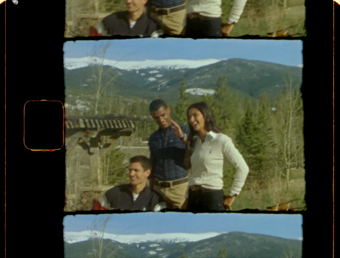 Four friends laughing by a wooden gate with the mountains behind them