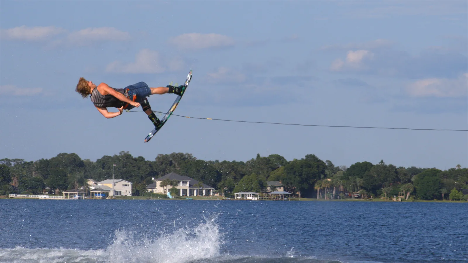 Wakeboarder in big air against a clean blue sky
