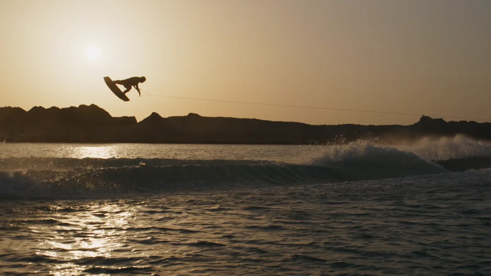 Wakeboarder silhouette mid-air at golden hour